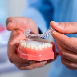 Dentist placing clear aligner on model of teeth