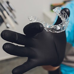 Dentist holding clear aligner with black gloves