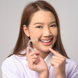 Woman smiling while pointing to clear aligner