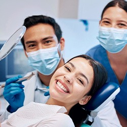 Patient smiling with dentist and dental assistant