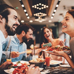 Group of friends smiling while eating lunch at restaurant