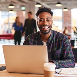 Man smiling while working on laptop in office