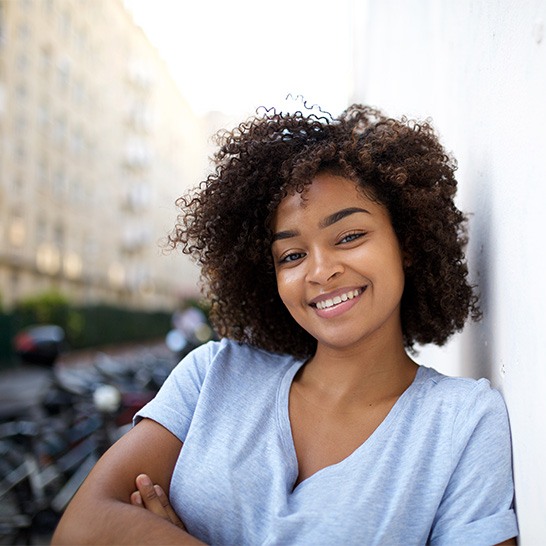 Woman leaning against a wall and smiling