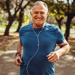 Man in blue shirt jogging down path in park