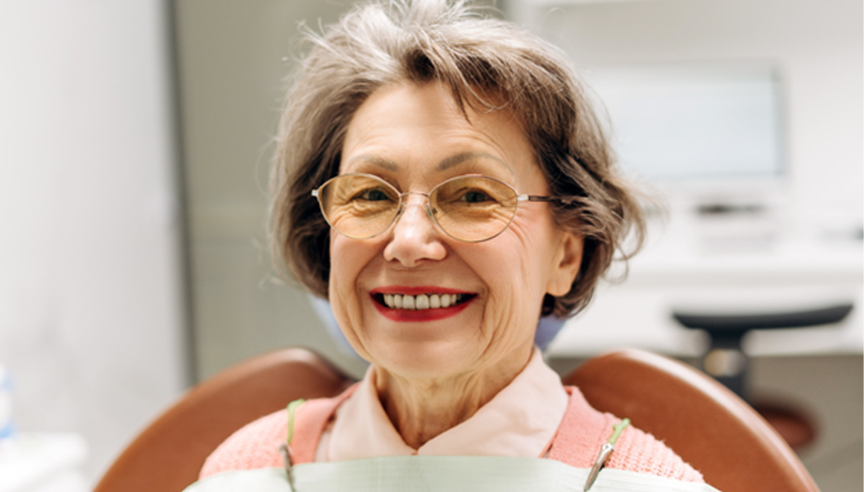 a close-up of a senior patient with dentures smiling