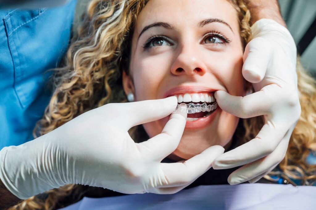 A woman having an Invisalign aligner put in her mouth by a dentist.